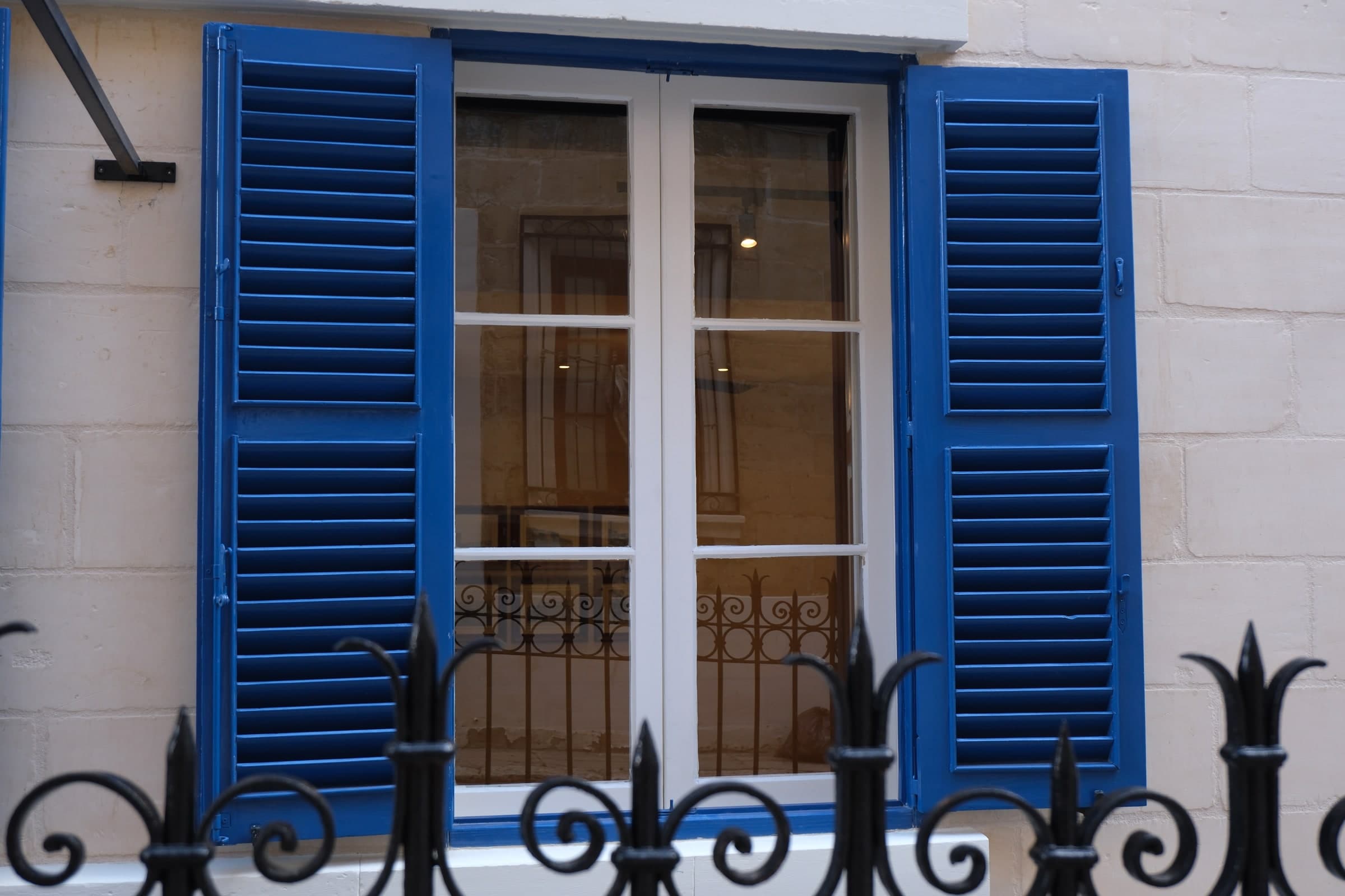 Limestone facade with blue shutters and traditional iron railings